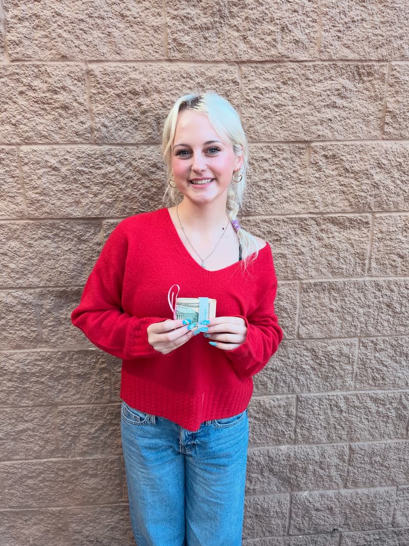 Student recipient holding $250 boost grant outside school